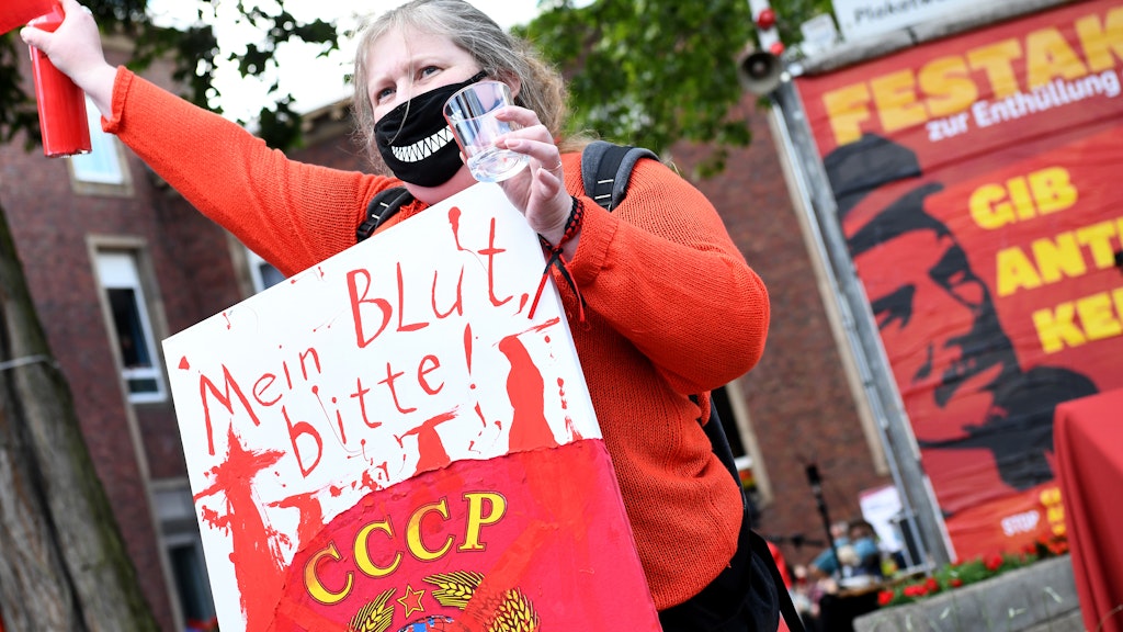 Eine Frau demonstriert mit einem Schild (Mein Blut, bitte!) gegen die Aufstellung der Lenin-Statue.