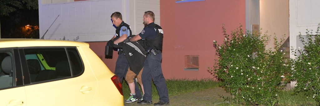 Polizisten führen den Tatverdächtigen ab. Der 27-Jährige soll seinen Bruder mit einem Küchenmesser erstochen haben.