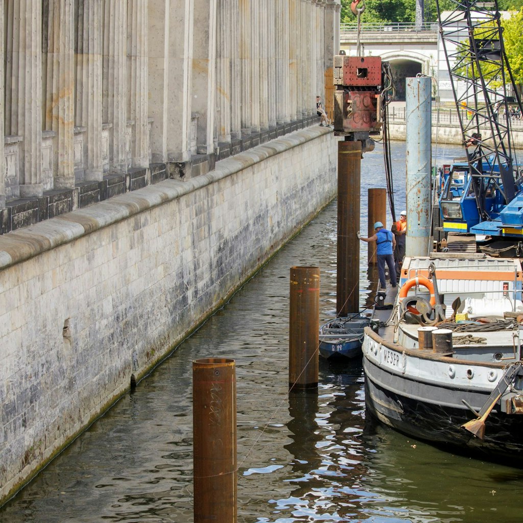 Eine Pfahlkonstruktion wird in das Flussbett gepresst. Dort soll dann das schwimmende Leitwerk befestigt werden.