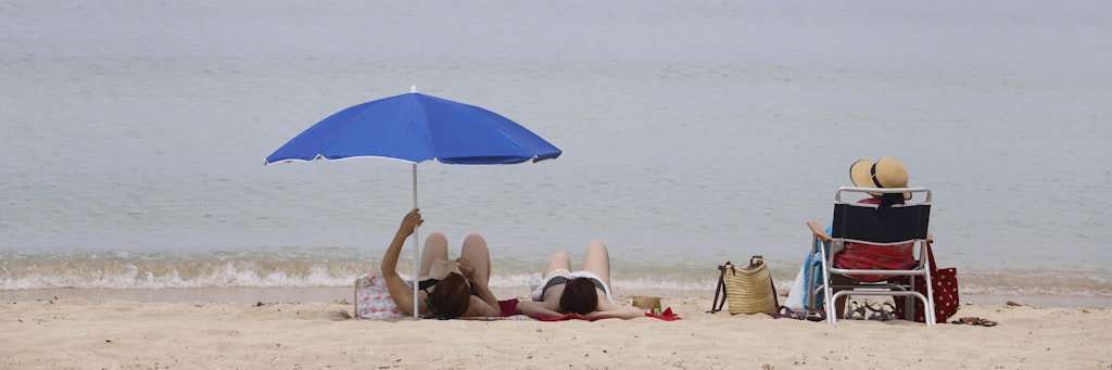 Menschen sonnen sich am Strand von Arenal. 