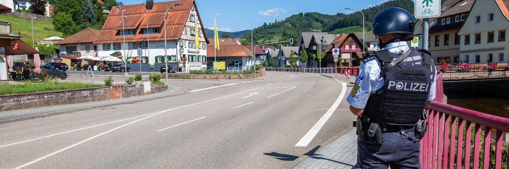 Baden-Württemberg, Oppenau: Ein Polizist sichert eine Straße im Ortskern. Ein Großaufgebot der Polizei sucht einen bewaffneten Mann.