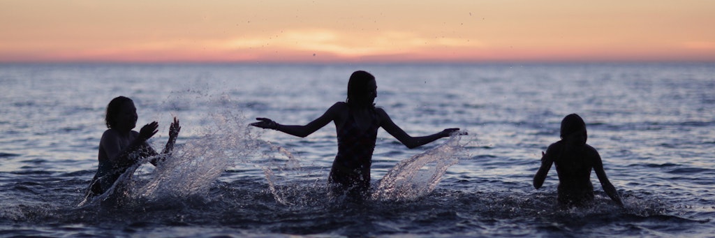 Kinder planschen im Meer.