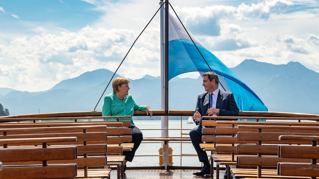Postkarten-Eintracht auf dem Chiemsee, mit weiß-blauer Fahne und Alpenkulisse: Angela Merkel und Markus Söder.