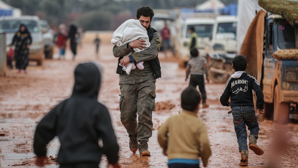 Ein Vater trägt sein Baby durch ein Behelfslager für Familien aus der umkämpften Provinz Idlib. Rund sieben Millionen Syrer haben wegen des blutigen Bürgerkriegs ihre Heimat verlassen.