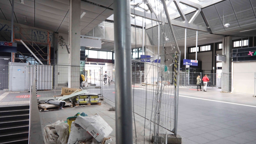 Die Empfangshalle des neuen Bahnhofsgebäudes. Baumaterial liegt herum, Bauzäune versperren den Weg.