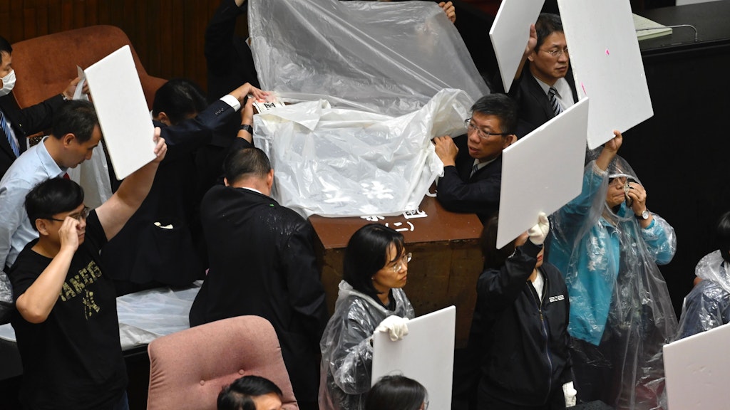 Abgeordnete der regierenden Demokratischen Fortschrittspartei (DPP) verteidigen sich im Parlament mit Tafeln, Plastikhüllen und Regencapes gegen Wasserbomben, die ihnen von der oppositionellen Kuomintang (KMT) entgegengeworfen werden.