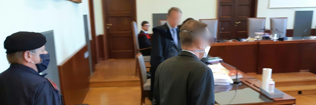 Der Angeklagte Banker wird von einem österreichischen Gendarmen in den Gerichtssaal geleitet.