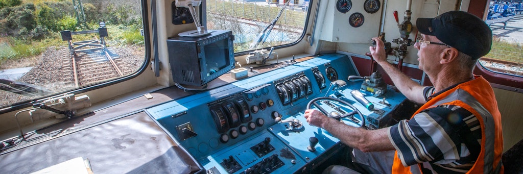 Werkstattleiter Jens Wolters fährt eine Elektrolokomotive aus dem Baujahr 1972 nach der Hauptuntersuchung über das Gleisnetz der Hafenbahn. In der Werkstatt in Mukran wurden zu DDR-Zeiten Schienenfahrzeuge von der russischen Breitspur auf das im restlichen Europa übliche Normalgleis umgespurt. Der Betrieb arbeitet heute alte Loks und Eisenbahnwaggons für den Einsatz bei privaten Eisenbahnunternehmen wieder auf. 