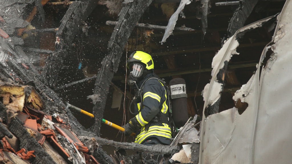 Ein Feuerwehrmann sucht in dem beschädigten Wohnhaus nach Spuren. Das Flugzeug war auf das Hausdach gestürzt.