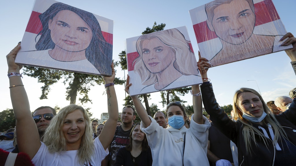 Begeistert halten Anhänger Porträts des Frauen-Trios bei einer Kundgebung in die Höhe.
