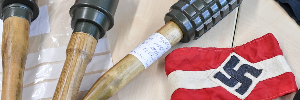 Sichergestellte Handgranaten und Materialien, darunter auch eine Armbinde mit einem Hakenkreuz, liegen bei einem Pressetermin im LKA Brandenburg auf einem Tisch nach einer Razzia gegen die Neonazi-Gruppe "Freie Kräfte Prignitz". 