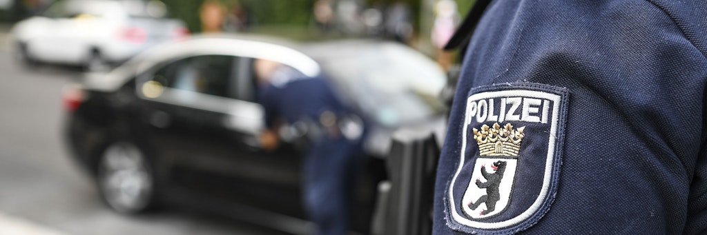 Polizisten ermahnen vor der GutsMuths-Grundschule in Mitte den Fahrer eines Elterntaxis.