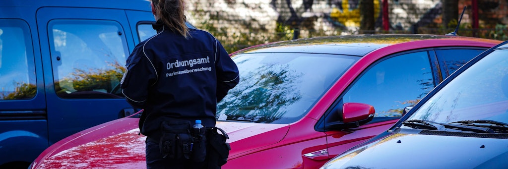 Eine Mitarbeiterin des Ordnungsamts verteilt Knöllchen an Autofahrer, die kein Parkticket gezogen haben.