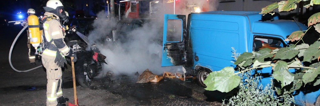 Ein Feuerwehrmann löscht in der Framstraße mehrere Fahrzeuge, die durch den Brandstifter in Flammen aufgingen. 