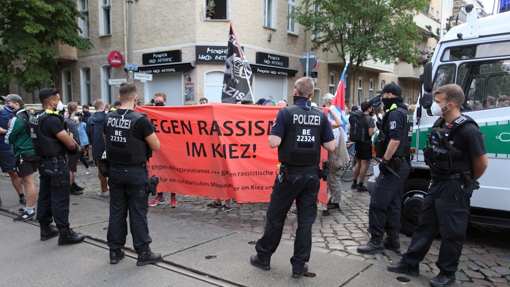 Polizisten sichern die angemeldete Kundgebung ab. Im Hintergrund ist die abgebrannte Kneipe „Morgen wird besser“ zu sehen. 