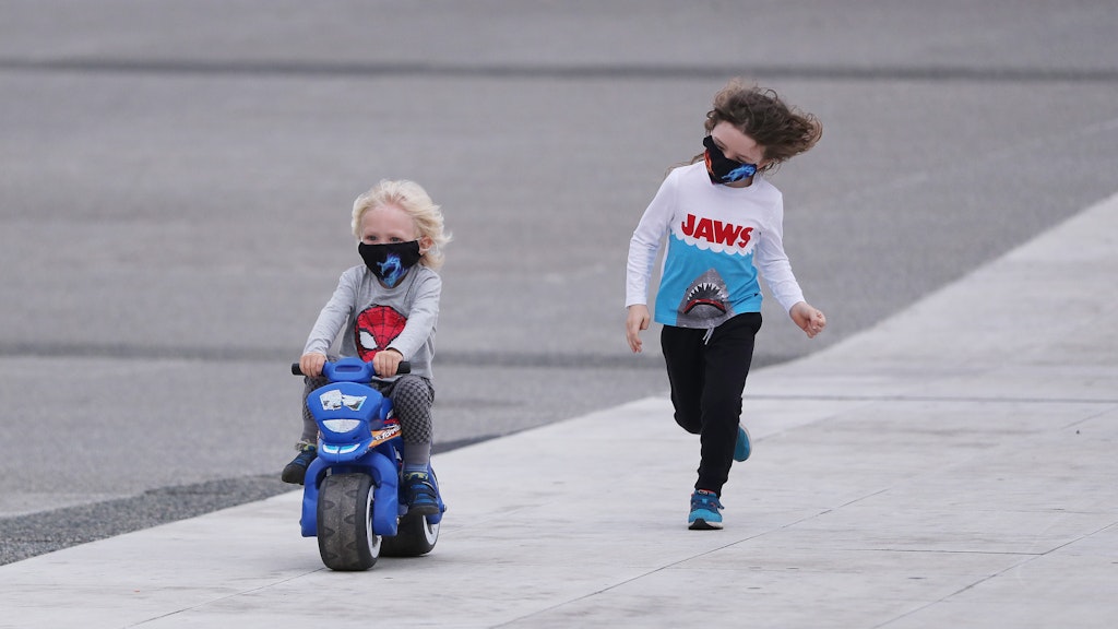 Kinder mit Schutzmasken spielen an einer Straße.