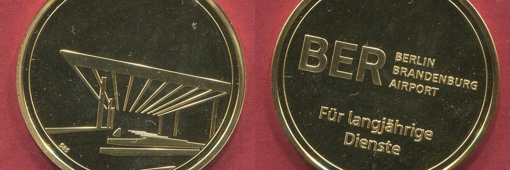 Auf der einen Seite die stilisierte Ansicht der Vorfahrt des BER, auf der anderen die Worte „BER Berlin Brandenburg Airport - Für langjährige Dienste“.