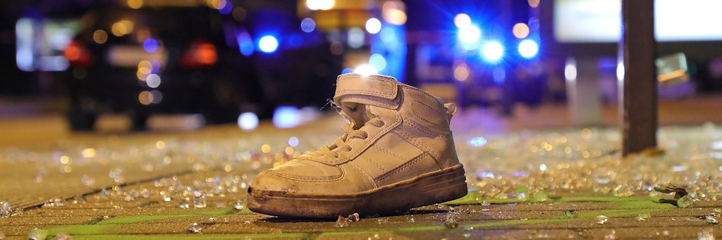 Ein einzelner Sportschuh liegt nach dem Verkehrsunfall an einer Bushaltestelle zwischen Glasscherben.