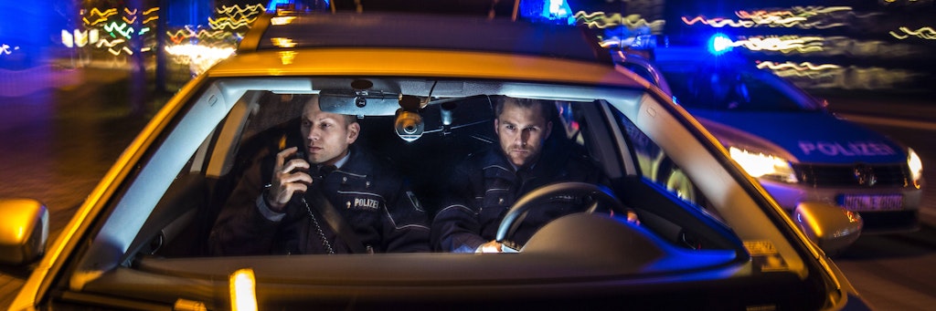 Polizisten sitzen in einem Streifenwagen (Symbolbild).