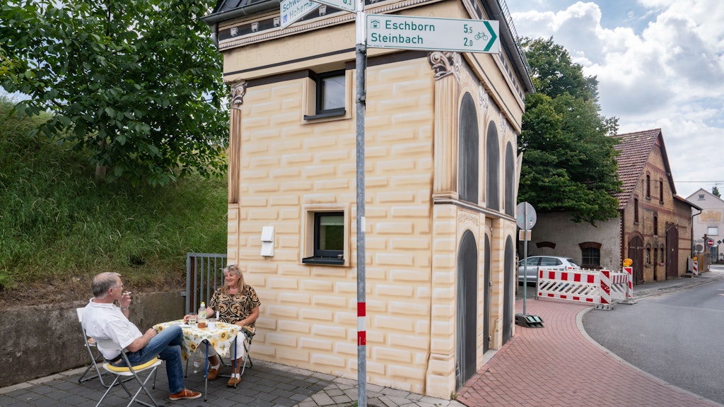 Achim Schollenberger (58) und seine Partnerin Simone Stiefel sitzen vor ihrem kleinen Wohnhaus am Campingtisch.