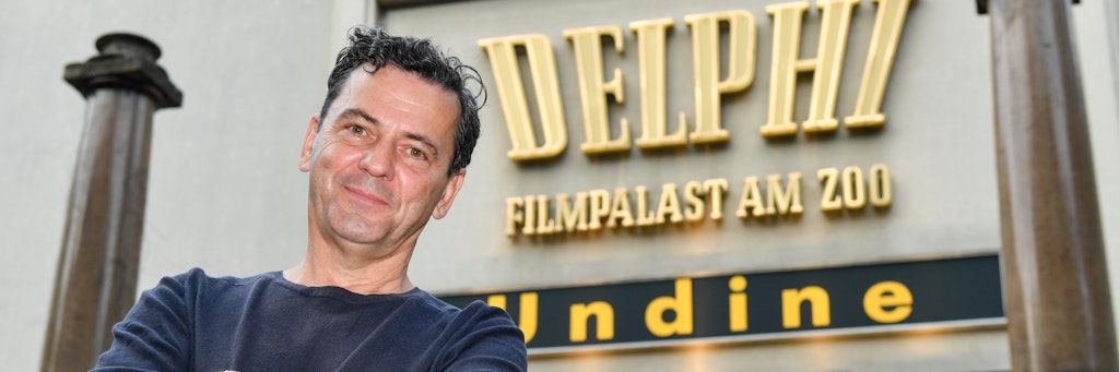 Filmregisseur Christian Petzold vor dem Kino Delphi am Zoo, vor der Werbung für seinen Film „Undine“. 