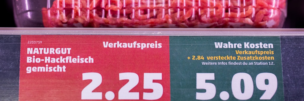 Ein Preisschild in einem Penny-Supermarkt weist neben dem Verkaufspreis auch den „wahren Preis“ aus. 