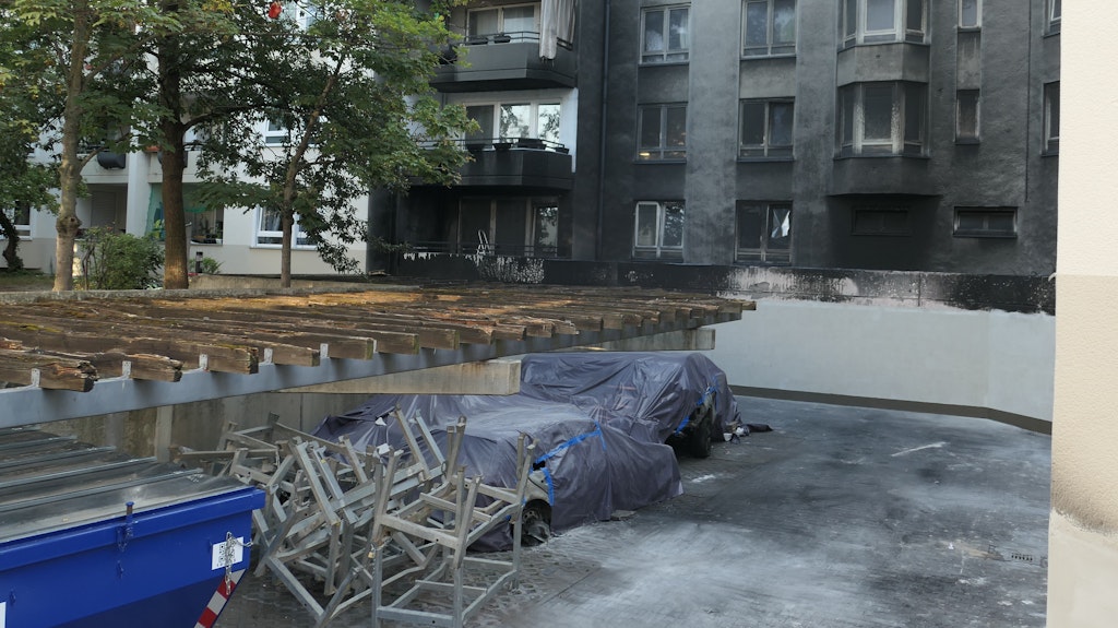 Die Tiefgarage ist zugemauert, das stützt das Haus. Im Vordergrund stehen abgedeckte Autowracks.