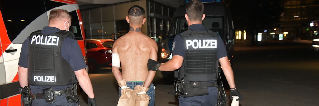 Polizisten führen den mutmaßlichen Messerstecher ab. Die Hände wurden in Papiertüten eingepackt, damit die Spuren der Tat nicht verloren gehen.