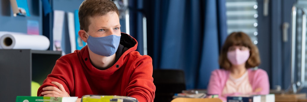 Schüler und Schülerinnen einer 12. Klasse des Lise-Meitner-Gymnasiums im bayrischen Unterhaching sitzen mit Maske im Unterricht.