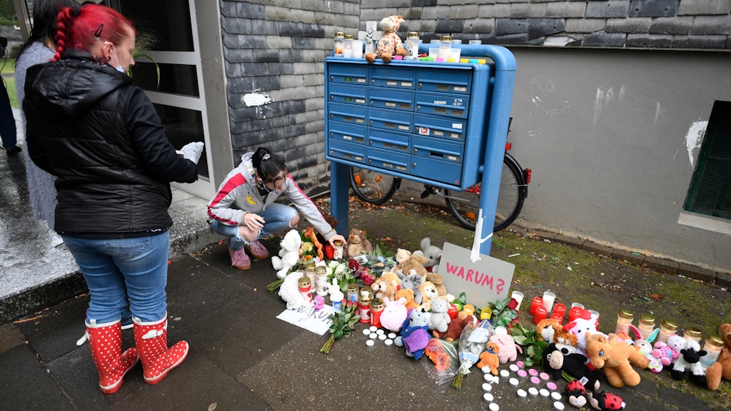 Eine Frau legt zum Gedenken an die toten Kinder Blumen und Kerzen an einem Briefkasten ab.