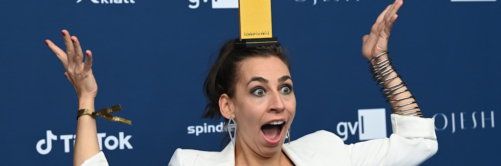 Schauspielerin Carol Schuler jongliert nach der Verleihung des Deutschen Schauspielpreises ihre Auszeichnung auf dem Kopf. 