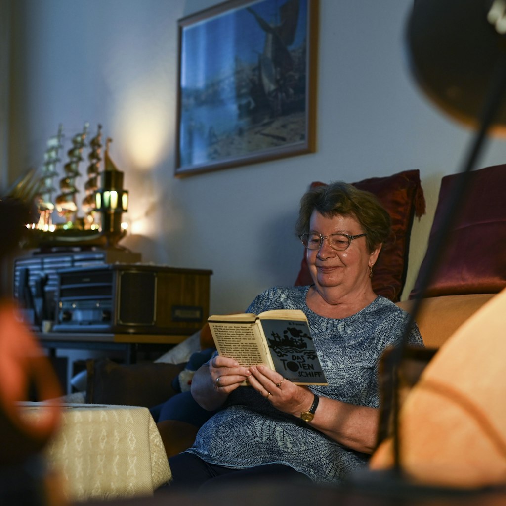 Monika Krannig in ihrem Wohnzimmer, sie liest am liebsten Abenteuerromane. Gereist ist sie nach wie vor nicht. 