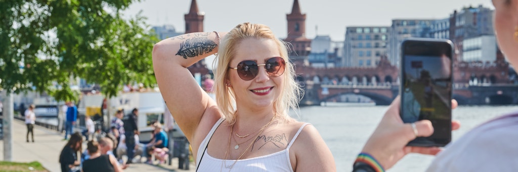 Sandra wird von ihrer Schwester Kim vor der Oberbaumbrücke fotografiert. Die beiden Touristen aus Nürnberg freuen sich über die spätsommerlichen Temperaturen während ihres Berlin-Kurztrips.