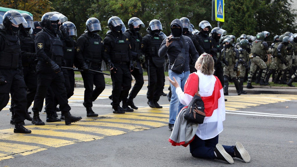 Eine Demonstrantin kniet vor einer Gruppe von Sicherheitskräften. Erneut gingen am Sonntag Zehntausende gegen Staatschef Lukaschenko auf die Straße.