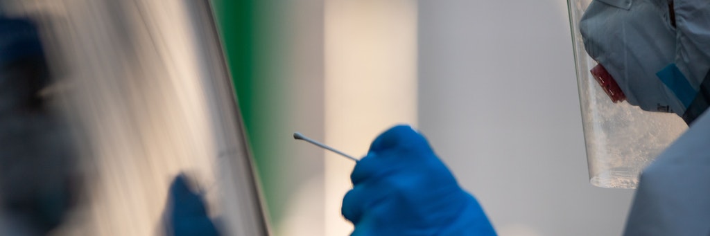 Ein Mitarbeiter testet per Stäbchen in einem Testzentrum eine Familie in einem Auto auf das Coronavirus. Nach einem heftigen Corona-Ausbruch im oberbayerischen Garmisch-Partenkirchen ist noch unklar, mit welchen Konsequenzen die mutmaßliche Verursacherin rechnen muss.