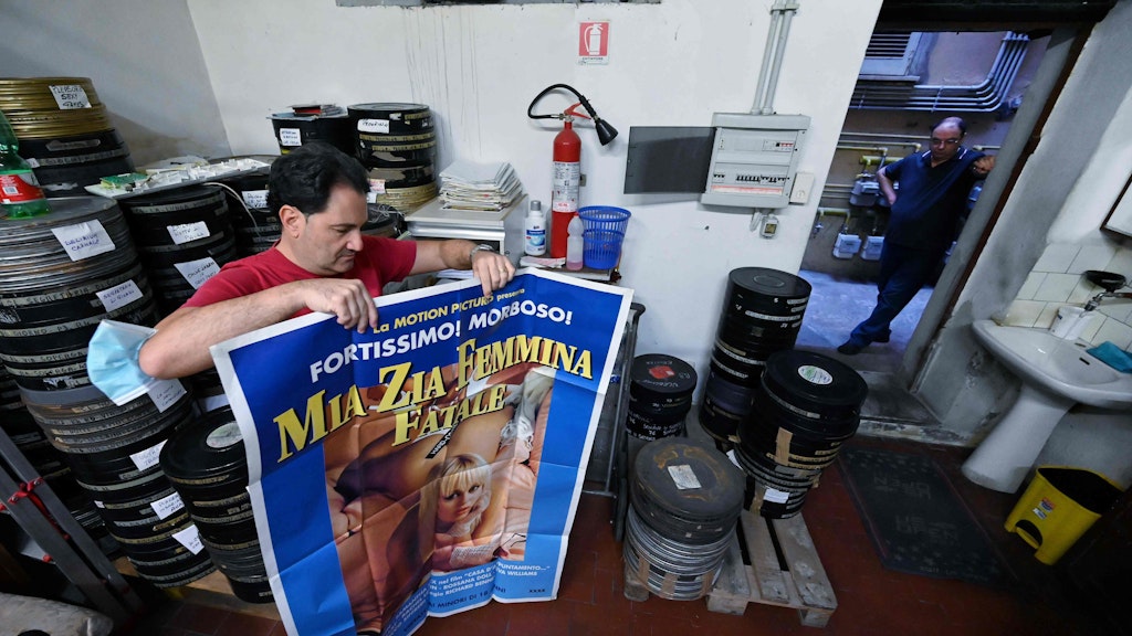 Geschäftsführer Carlo zeigt sein Lager mit Filmrollen und ein Plakat eines Porno-Films, den das „Ambasciatori“ im Angebot hat.