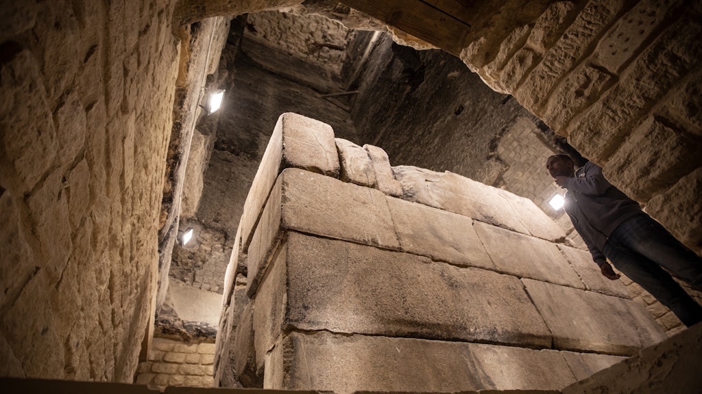 Ein Mann steht neben einem Sarkophag in der Pyramide von Djoser im ägyptischen Saqqara.