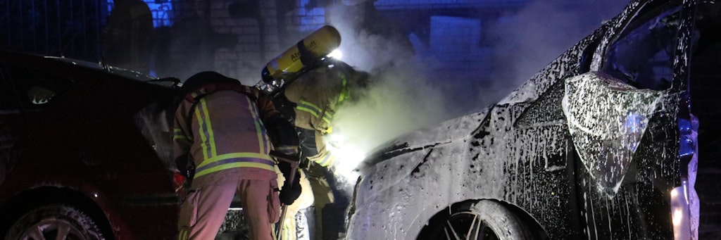 Feuerwehrleute löschen die brennenden Autos in der Schandauer Straße.