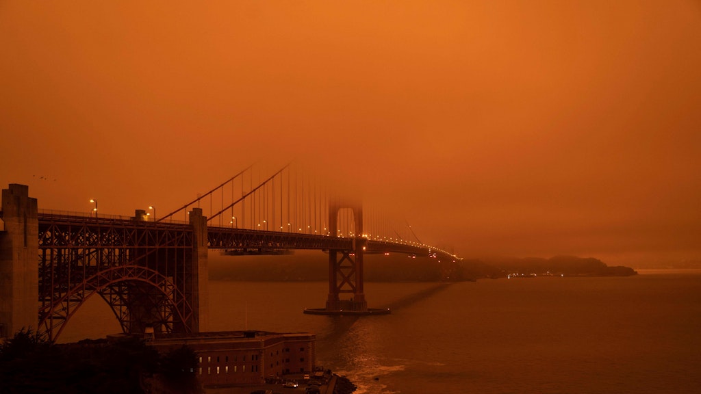 Die Golden Gate Bridge in San Francisco ist in dichten Rauch gehüllt. Alles ist in ein dunkles Orange getaucht.