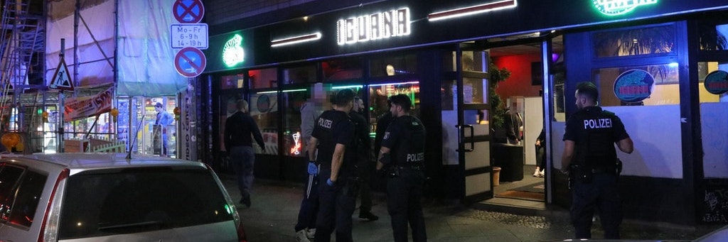 Einsatzkräfte der Polizei stehen in der Nacht zu Sonntag nach der Festnahme des Mannes vor einer Bar in Neukölln.