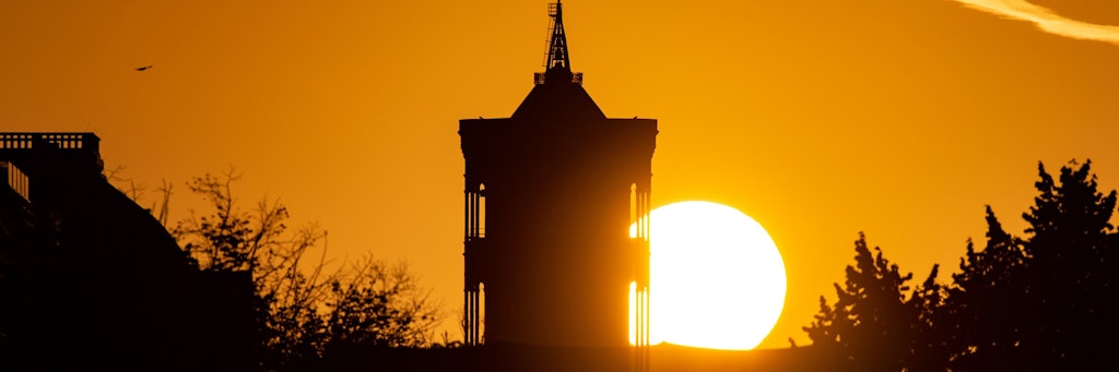 Die Sonne geht hinter dem Turm des Roten Rathauses auf.