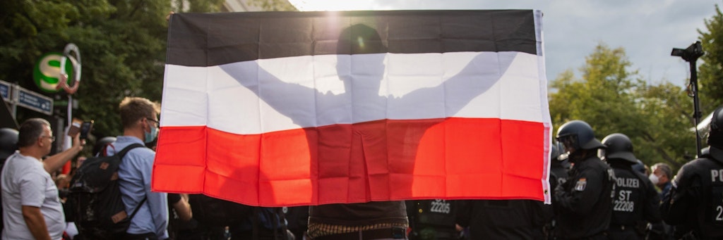 Corona-Demo in Berlin: Ein Mann hält eine Reichsflagge hoch. 