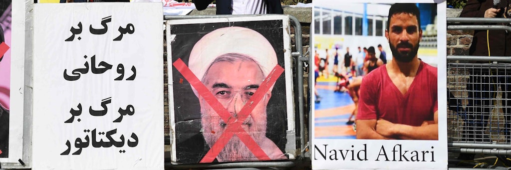 Bei einer Demo zeigten Protestierende das Foto von Navid Afkari neben dem durchgestrichenen Porträt des iranischen Präsidenten Hassan Rouhani (l.)