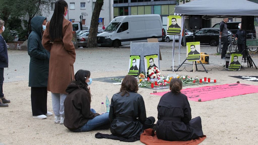 in stillem Gedenken an Hussam Fadl: Nach einigen Redebeiträgen ließen sich einige Teilnehmer vor dem Denkmal nieder. 
