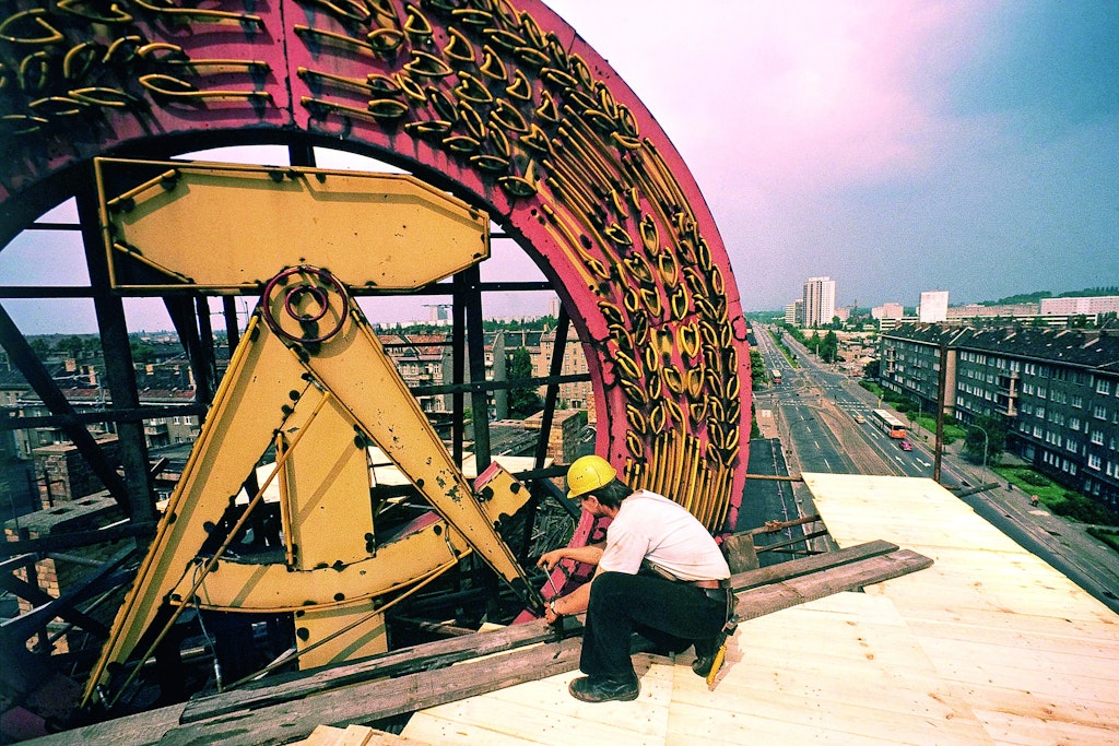Am Ende. Ein Arbeiter auf einem Hochhaus in Ost-Berlin beginnt mit dem Abbau des Staatswappens der DDR. Die Volkskammer hat am 31. Mai 1990 beschlossen, das Emblem von allen öffentlichen Gebäuden zu entfernen. Der Abriss der Berliner Mauer beginnt zwei Wochen später.