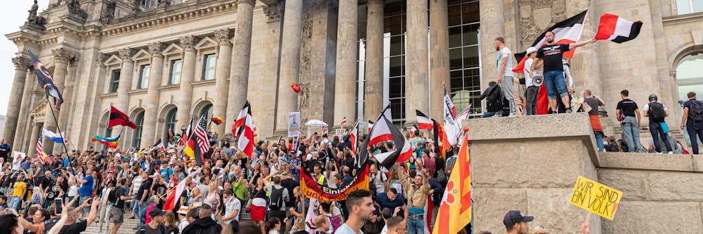 Teilnehmer einer Kundgebung gegen die Corona-Maßnahmen stehen auf den Stufen zum Reichstagsgebäude. 