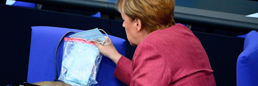 Angela Merkel steckt im Bundestag eine Tüte mit Masken in ihre Handtasche.