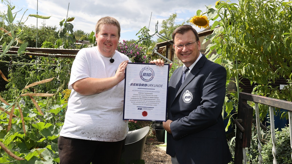 Olaf Kuchenbecker (rechts) vom Rekordinstitut für Deutschland überreicht Patrick Teichmann die Rekordurkunde in seinem Schrebergarten in Pößneck.