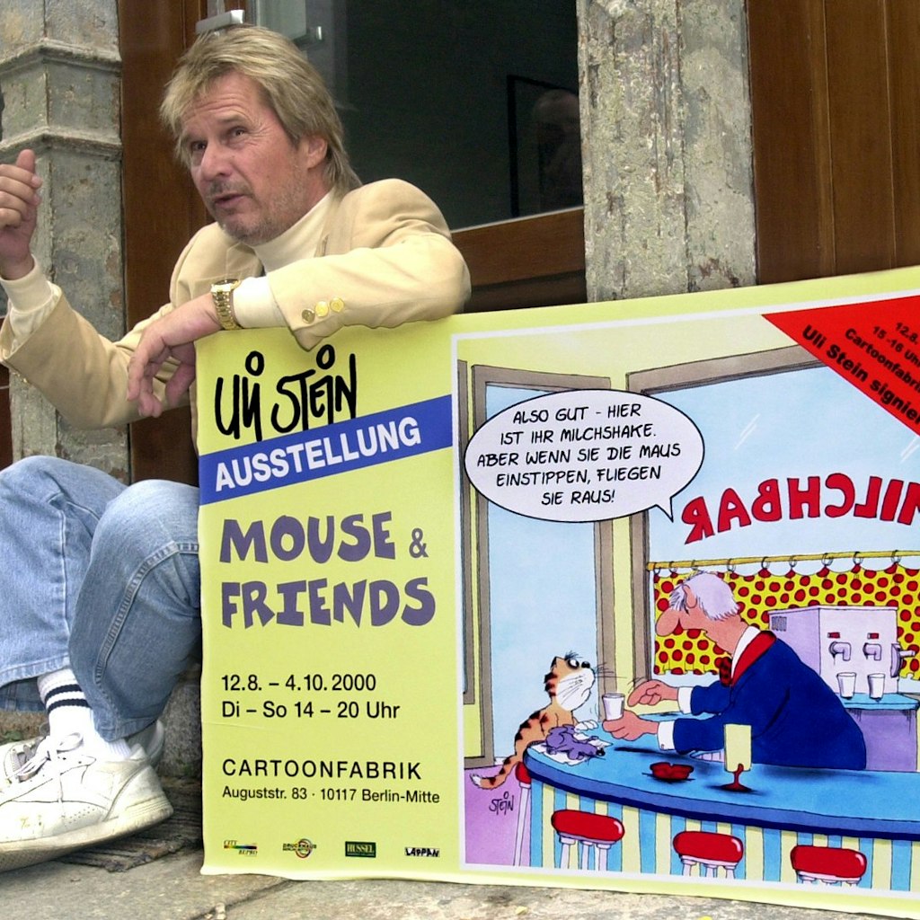 Mit dem Plakat zu seiner Ausstellung zeigt sich der Cartoonist Uli Stein im Jahr 2000 vor der Galerie „Cartoonfabrik“ in Berlin.