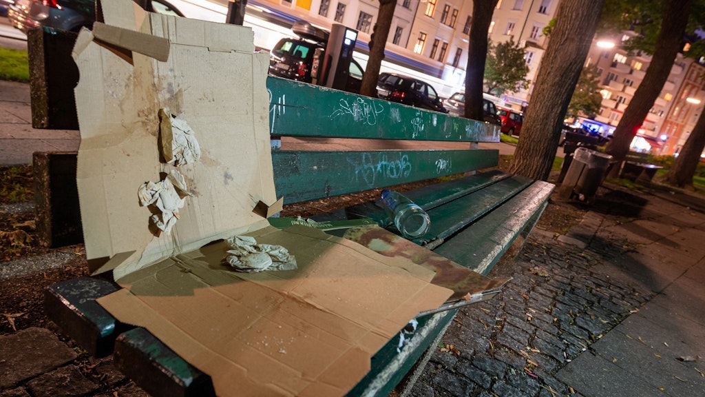 Ein leerer Pizzakarton liegt auf einer Parkbank in München.